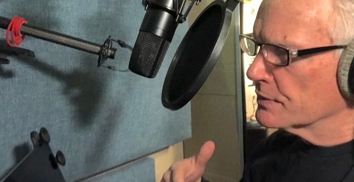 Röstskådespelare med hörlurar framför mikrofon i inspelningsstudio